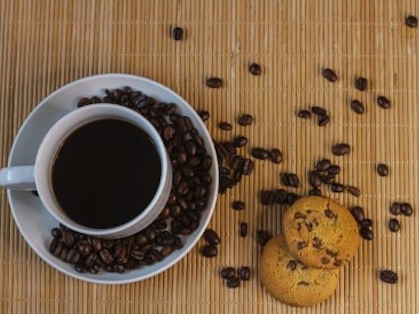 コーヒーカップと散りばめられたコーヒー豆とチョコチップクッキー